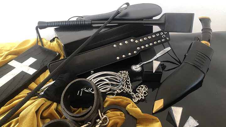 an image of leather materials including a spanking device, handcuffs, knife, and a couple sharp objects.